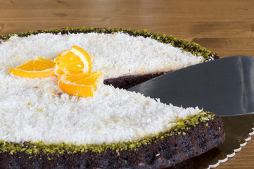 Closeup of a sliced delicious chocolate cake with coconuts and orange slices