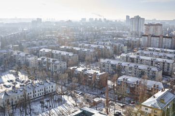 Fototapeta na wymiar The aerial View of residential district Darnitsa in Kyiv,Ukraine in sunny winter day.View over the city rooftops with sunlight and snow.Moderns buildings at Industrial uptown,residential neighbourhood