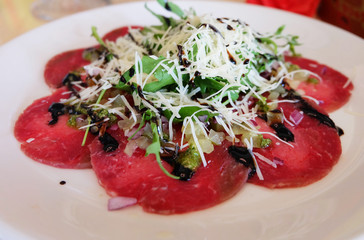 Beef carpaccio with cheese and herbs.