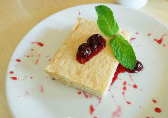 The cake is napoleon decorated with strawberry jam and mint.