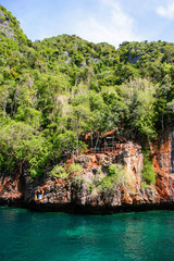 Great and large rocks in the ocean. Small islands with green forest and palms. Blue sky with...