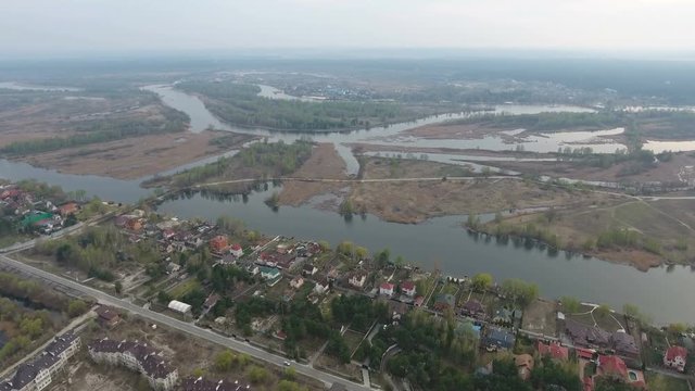 Original aerial shot of the Dnipro river with curvy river bank, full of summer cottages, green gardens, forest boscages, small inflows , little islets in Ukraine in a sunny day in spring
