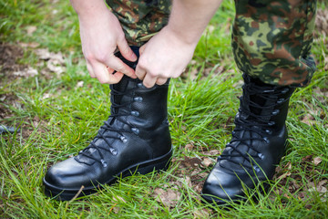 german soldier laces his boots on grass