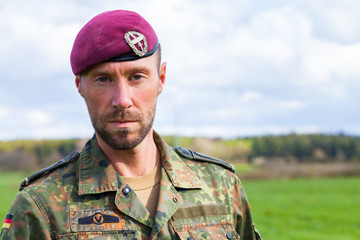 german soldier with a beret stands on a field background