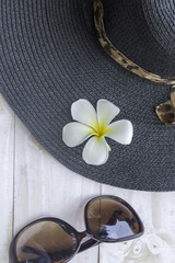 Summer hat with sunglasses on white wooden background.