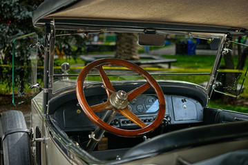 Wooden Steering wheel of a classic vintage car. - obrazy, fototapety, plakaty