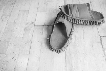 The slippers on the wood floor in black and white tone.