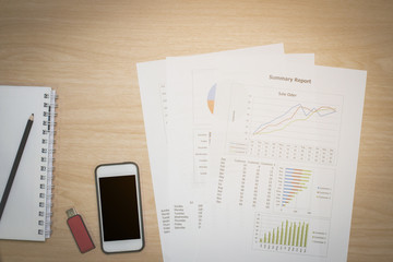 Top view Desks for business consisted of mobile phones, flash drive, and reported sales