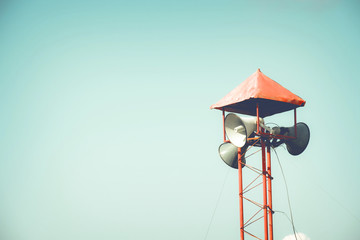 Vintage Horn speaker for public relations sign symbol on blue sky background. vintage color tone effect.