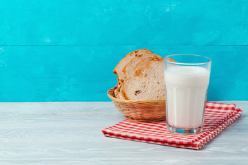 Milk and bread on wooden table over blue background with copy space. Jewish holiday Shavuot concept