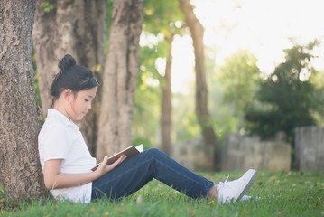 Asian Girl reading a book under the tree