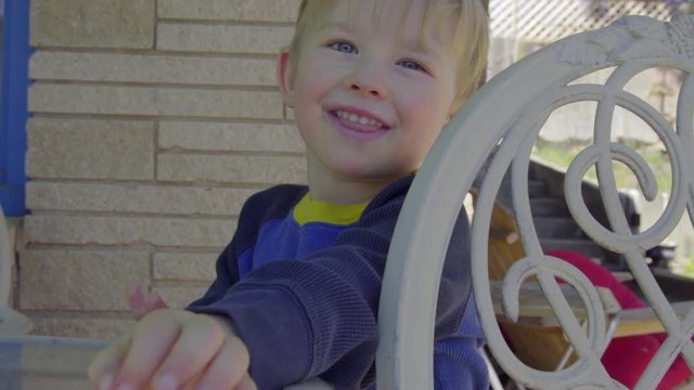 Adorable kids flips toy frog in his backyard on a sunny day