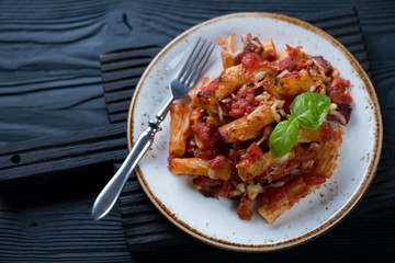 Plate with italian ziti over black wooden background, selective focus, horizontal shot