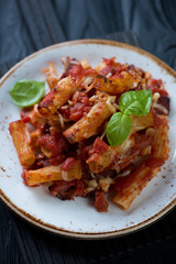 Close-up of italian ziti served on a glass plate, vertical shot, selective focus