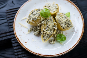 Close-up of baked conchiglioni stuffed with spinach and cheese and served on a plate, selective focus, horizontal shot