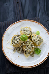 Glass plate with baked conchiglioni with cheese and spinach stuffing, black wooden background, vertical shot