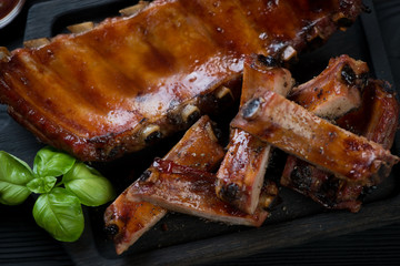 Close-up of whole and sliced baked pork ribs, selective focus, horizontal shot