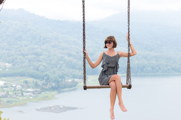 Sexy young aldy swinging over the precipice on the magic tropical Bali island, Indonesia.