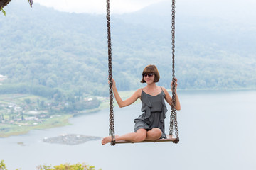 Sexy young aldy swinging over the precipice on the magic tropical Bali island, Indonesia.