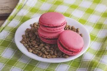 Pink macarons on the plate with green coffee beans