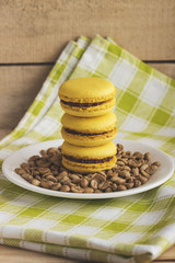 Yellow macarons on the plate with green coffee beans