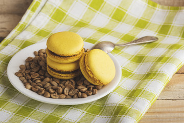 Yellow macarons on the plate with green coffee beans