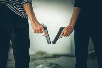 Two Robbers holding a gun at abandoned building. Low key photo and selective focus. criminality concept.