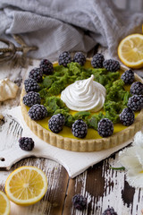 Delicious homemade lemon tart. Pie on rustic white table. Tart with blackberry and meringue