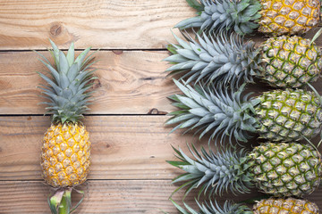 Row of pineapple fruits on wooden table background.