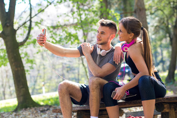 Young couple sitting on bench at the park and relaxing after jogging.