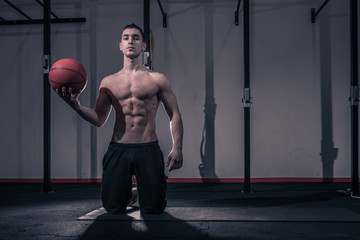 one young man, bodybuilder kneeling ball