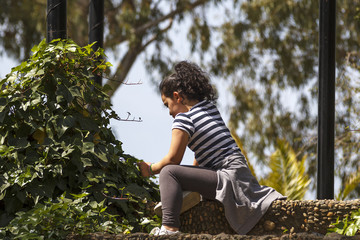 Niña morena rizosa jugando y danzando en el parque