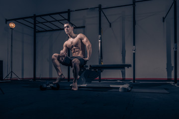Fototapeta na wymiar one young man, low angle view, bodybuilder muscular sitting posing