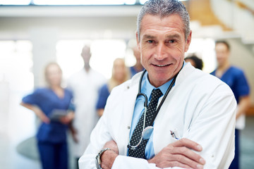 Portrait of smiling doctor standing with arms crossed