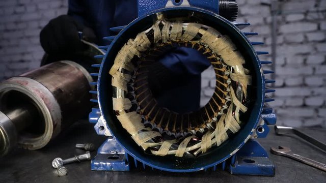 Worker removes the electric motor rotor. Repair of industrial electric motor.