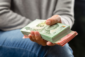 Close up view of women holding a lot of money in hand, Thai Baht banknotes.