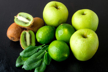 Ingredients for smoothie. Green fruits on black wooden background. Apple, lime, spinach, kiwi. Detox. Healthy food.