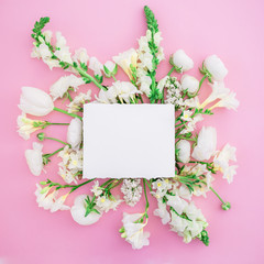 Frame of paper card and white flowers isolated on pink background. Flat lay. Top view