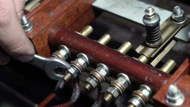 Worker twists the terminals of industrial transformer.
