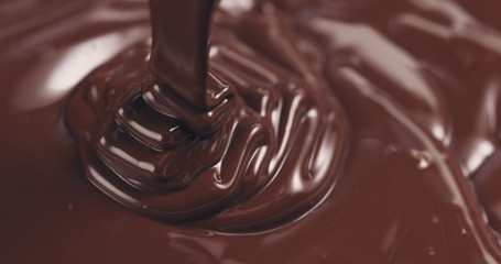 premium dark melted chocolate being poured from spoon closeup toned, 4k photo
