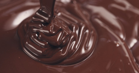 premium dark melted chocolate being poured from spoon closeup toned, 4k photo