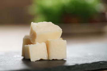 pieces of hard parmesan cheese on slate board, closeup photo