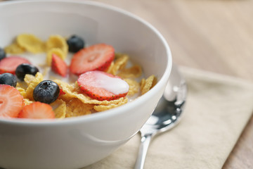 healthy breakfast with corn flakes and berries in white bowl, shallow focus