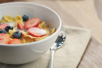 healthy breakfast with corn flakes and berries in white bowl, slightly toned photo