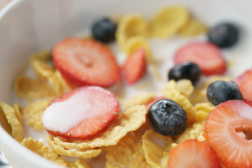 closeup of healthy breakfast with corn flakes and berries in white bowl, macro shot