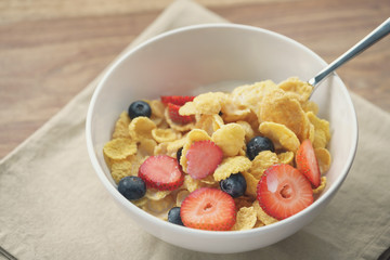 spoon with healthy breakfast with corn flakes and berries, slightly toned photo