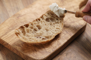 spreading ricotta cheese on fresh rustic bread, shallow focus