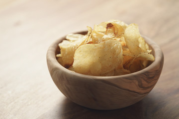 potato chips with herbs in wood bowl on rustic table