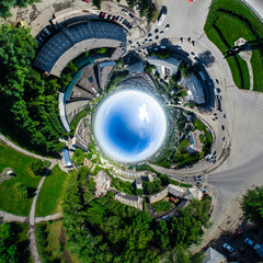 Aerial city view with crossroads and roads, houses, buildings, parks and parking lots, bridges. Copter shot. Little planet mode. Full sphere.