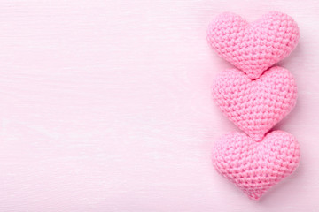 Crochet pink hearts on pink wooden background